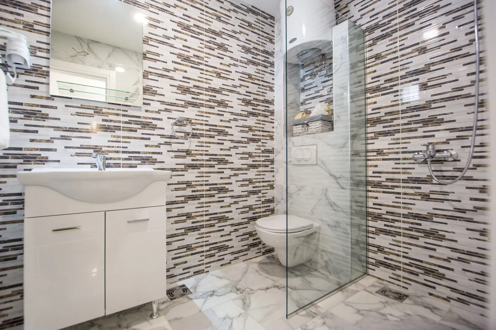 Modern bathroom with a sink, walk-in shower, and a wall-mounted toilet.