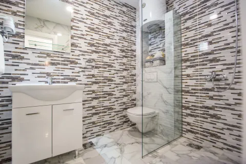 Modern bathroom with a sink, walk-in shower, and a wall-mounted toilet. - image 9