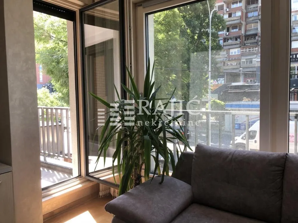 Living room with a sofa and a large window overlooking the street.