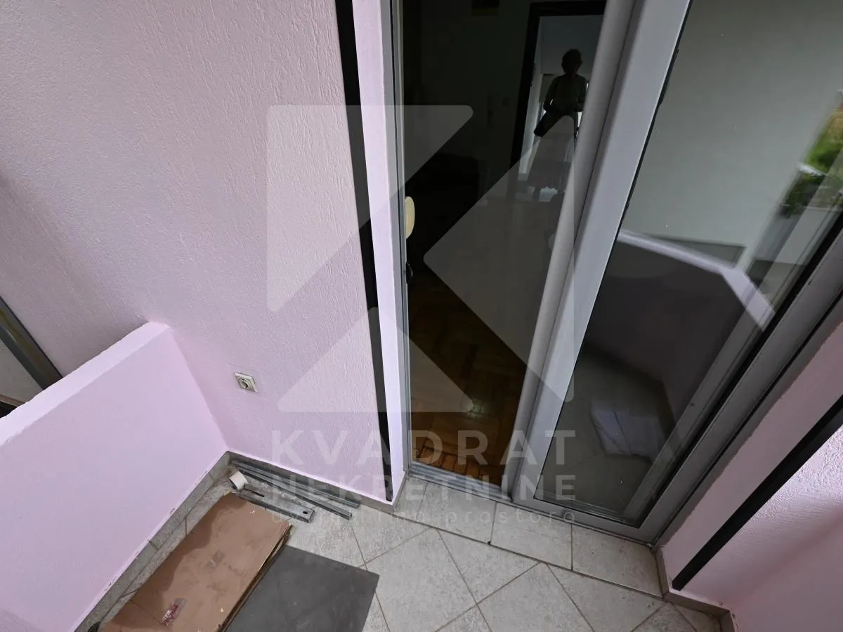 Small tiled balcony with light walls and access to the interior.