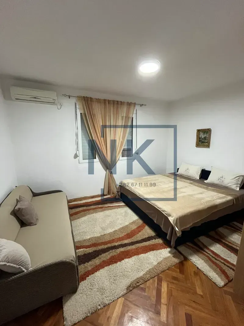Furnished bedroom with a double bed, sofa, and air conditioning.