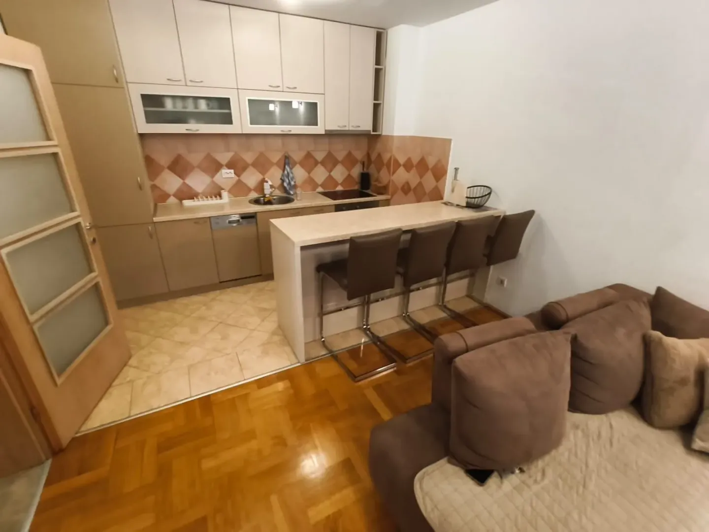 Small kitchen with a breakfast bar and bar stools connected to the living room.