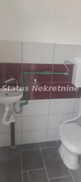 Small bathroom with a sink and toilet tiled with ceramic tiles. - image 4