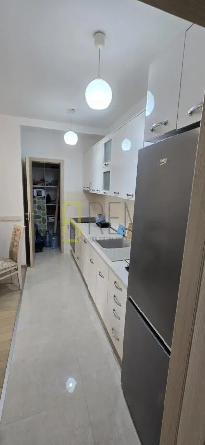 Moderna kuhinja sa bijelim elementima i frižiderom.