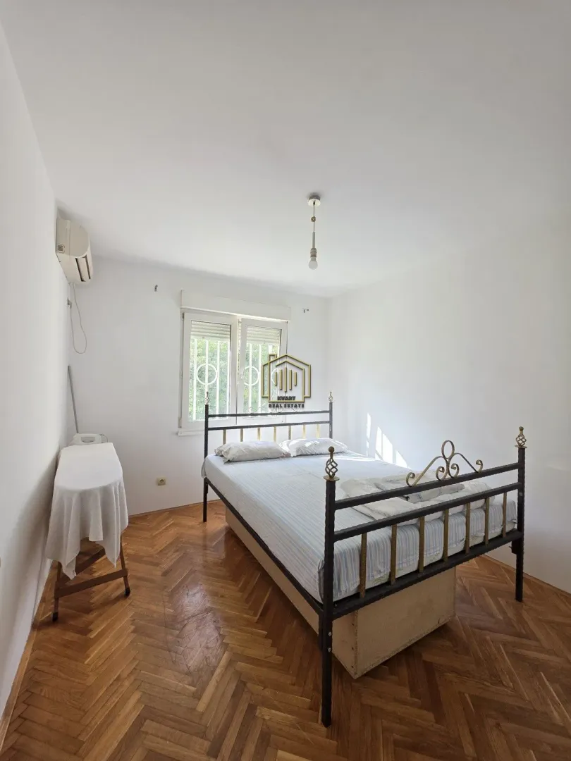 Spavaća soba sa bračnim krevetom i drvenim podom.