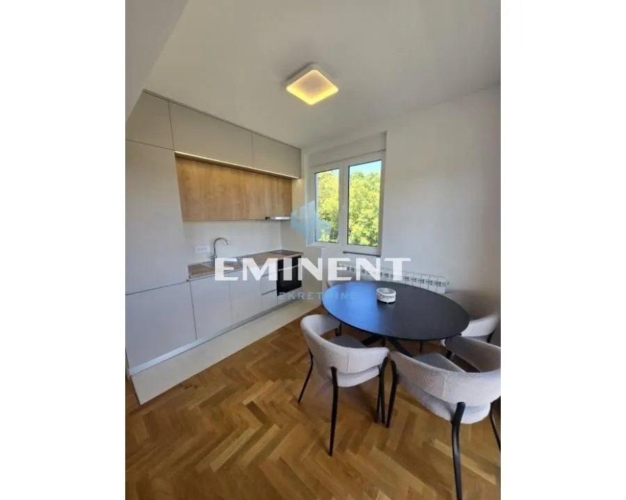 Modern kitchen with a dining table and hardwood flooring.