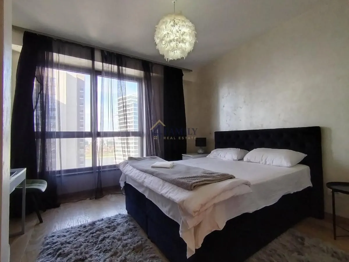 Bright bedroom with a double bed and a large window.