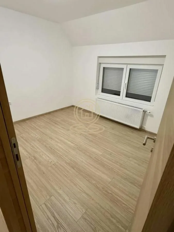 Prazna soba sa laminatom i belim zidovima.