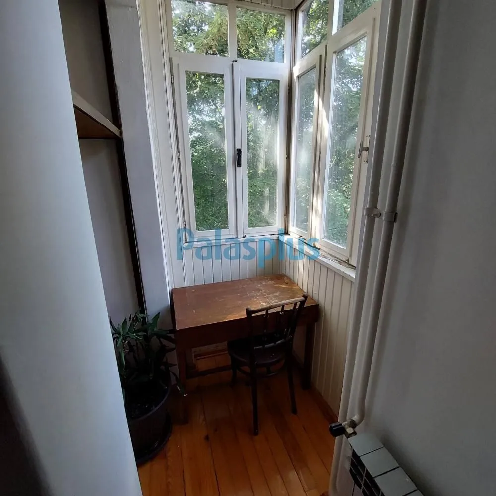 Zastakljeni balkon sa radnim stolom i stolicom.