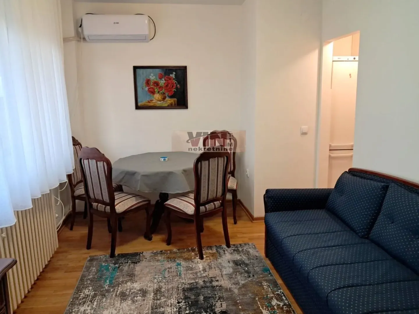 Living room with a sofa set, dining table, and air conditioning unit.