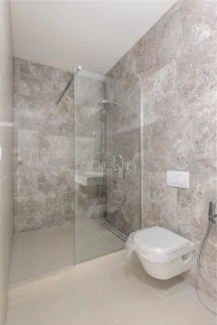 Moderne kupatilo sa tuš kabinom i ugradnom šoljom obloženo mermernim pločicama. - image 6