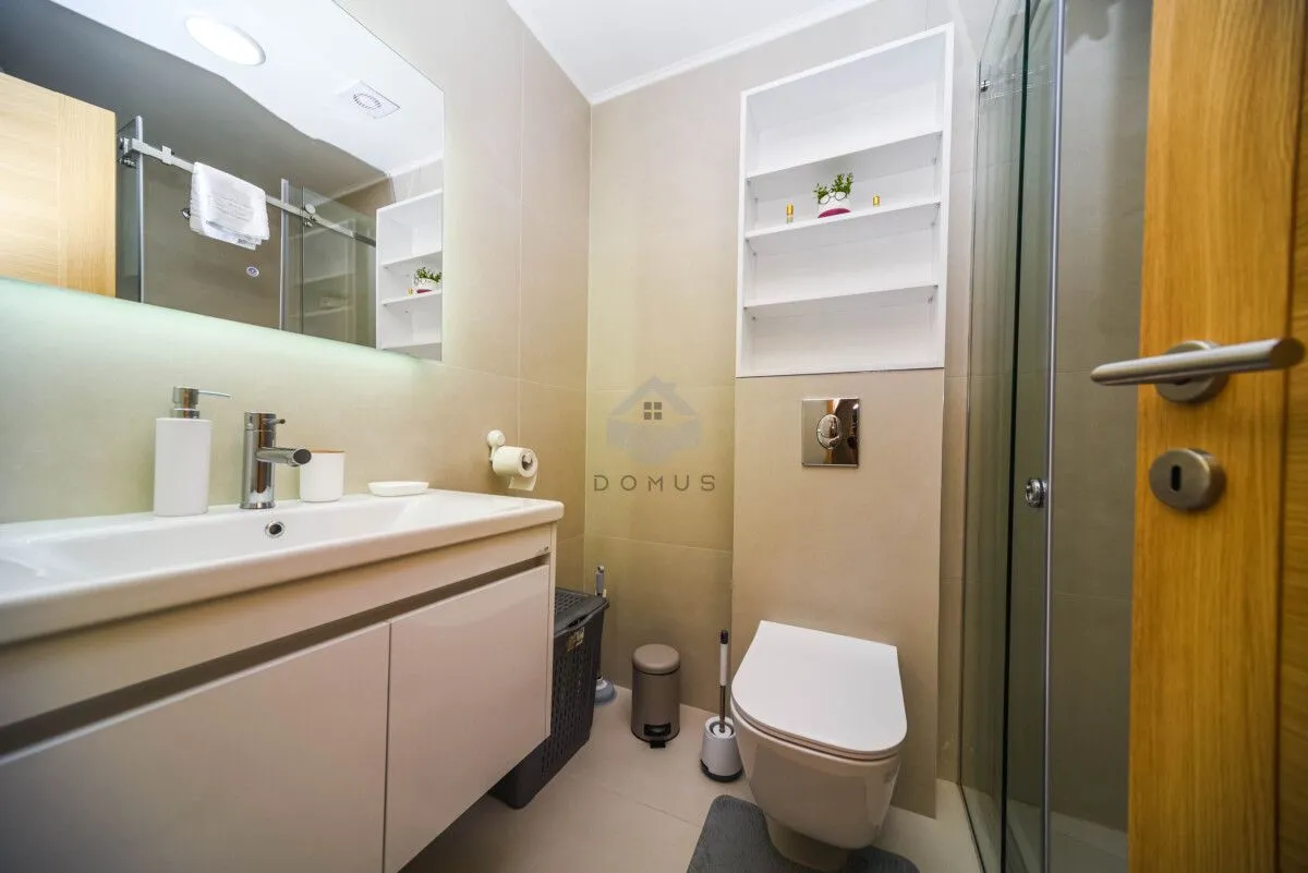 Modern equipped bathroom with a washbasin, toilet, and shower cabin.