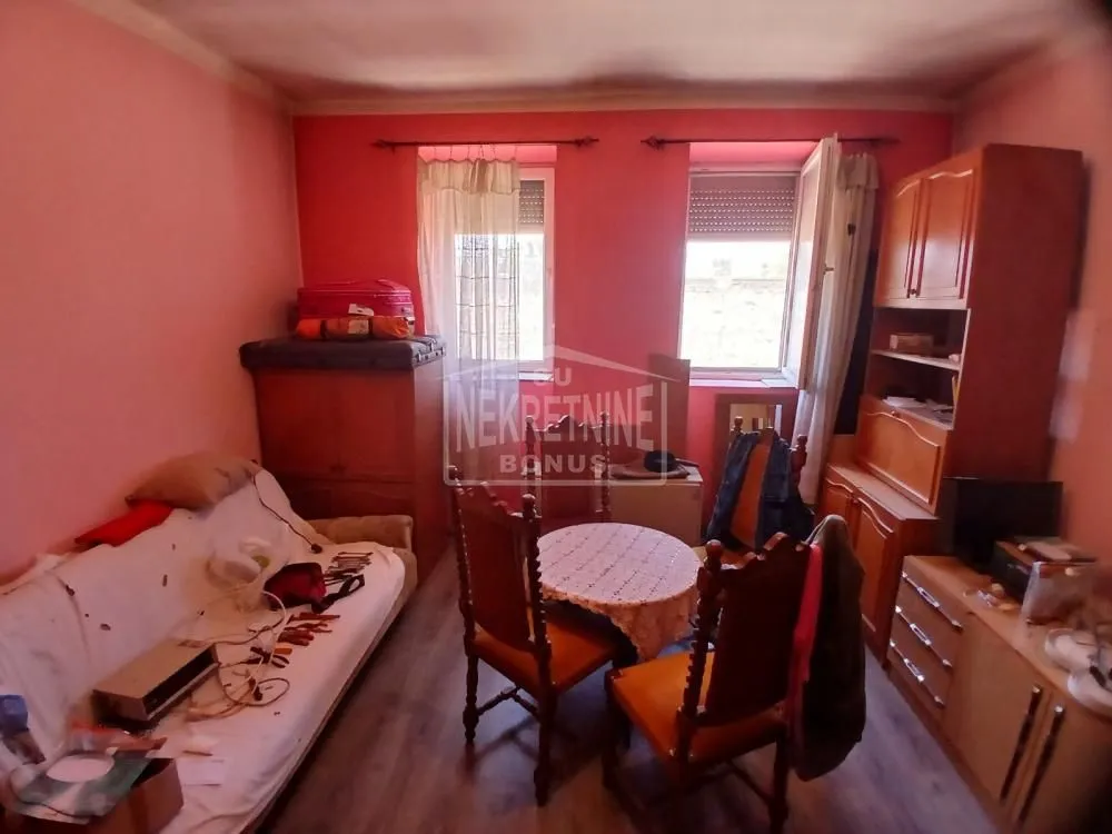Dnevna soba sa garniturom za sedenje, trpezarijskim stolom i drvenim nameštajem.