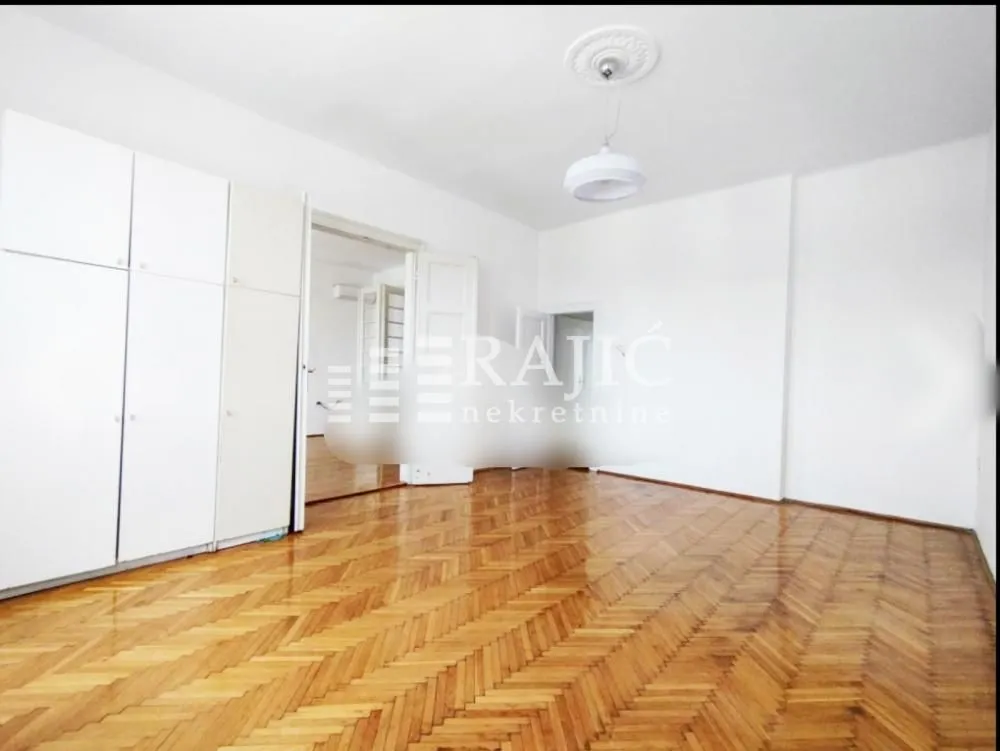 Empty room with hardwood parquet flooring and built-in closet.