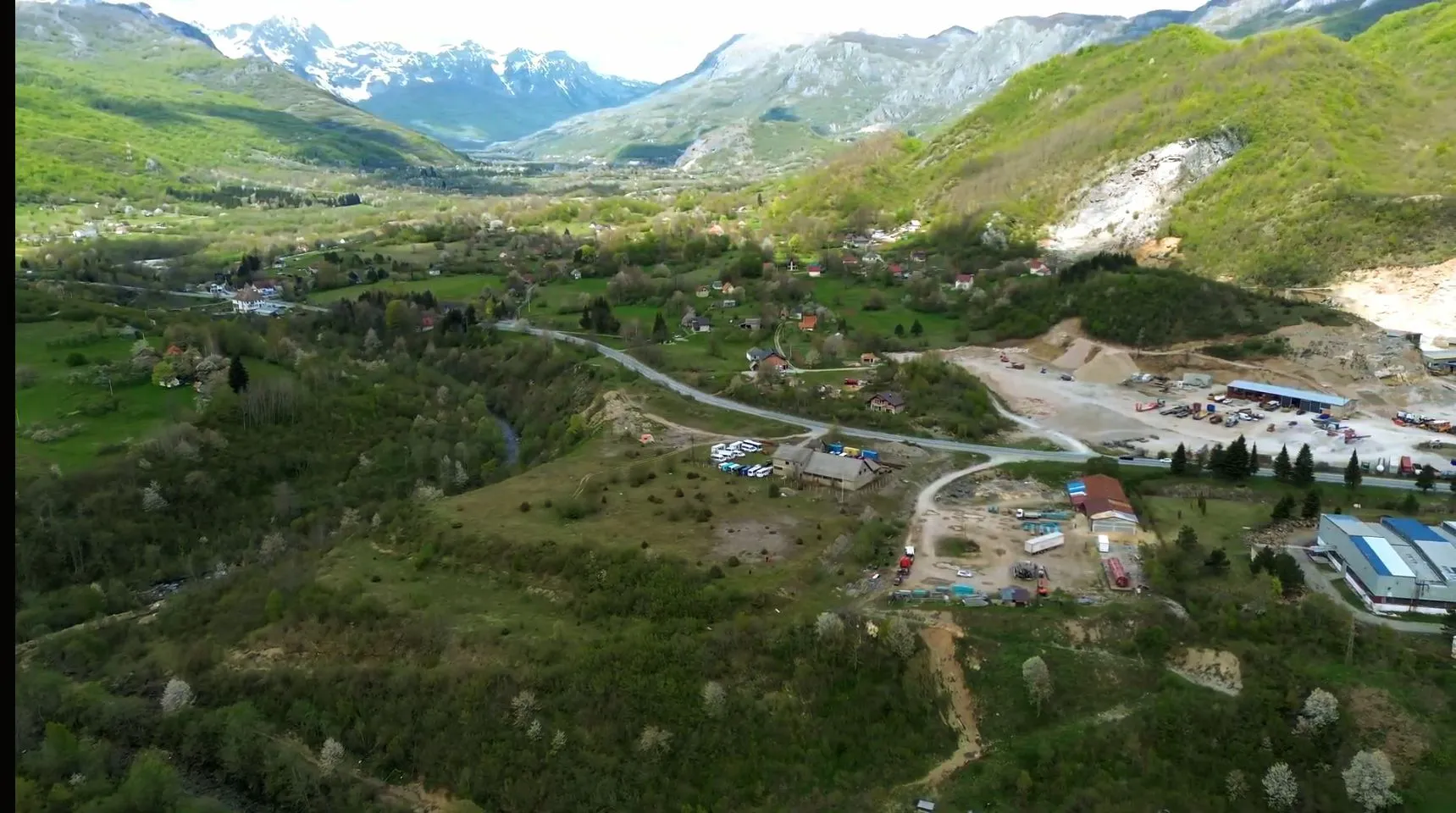 Pogled iz vazduha na planinski pejzaž i okolno naselje.