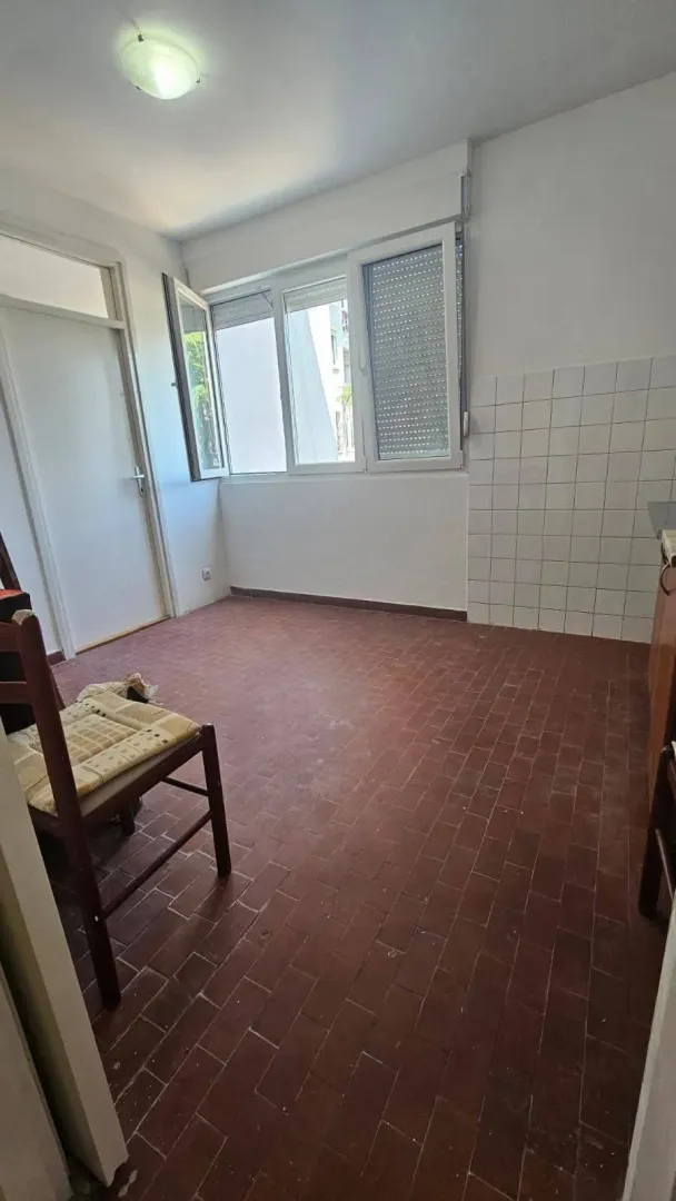 Manja prazna kuhinja sa pločicama na podu i na zidu.