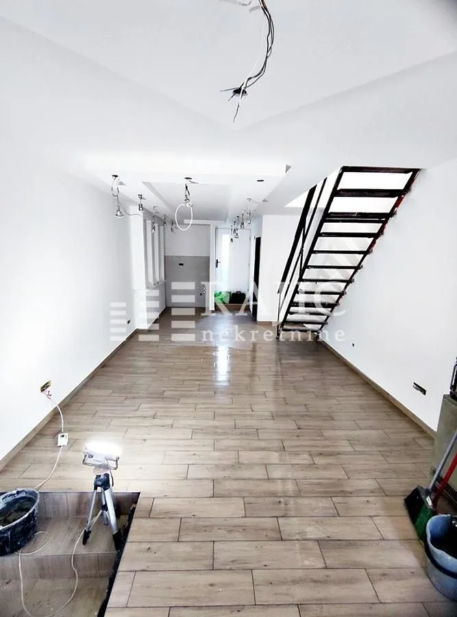 Unfurnished space under construction with wooden stairs.