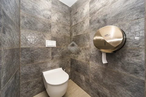 Modernly equipped bathroom with grey-brown tiles and a toilet. - image 11