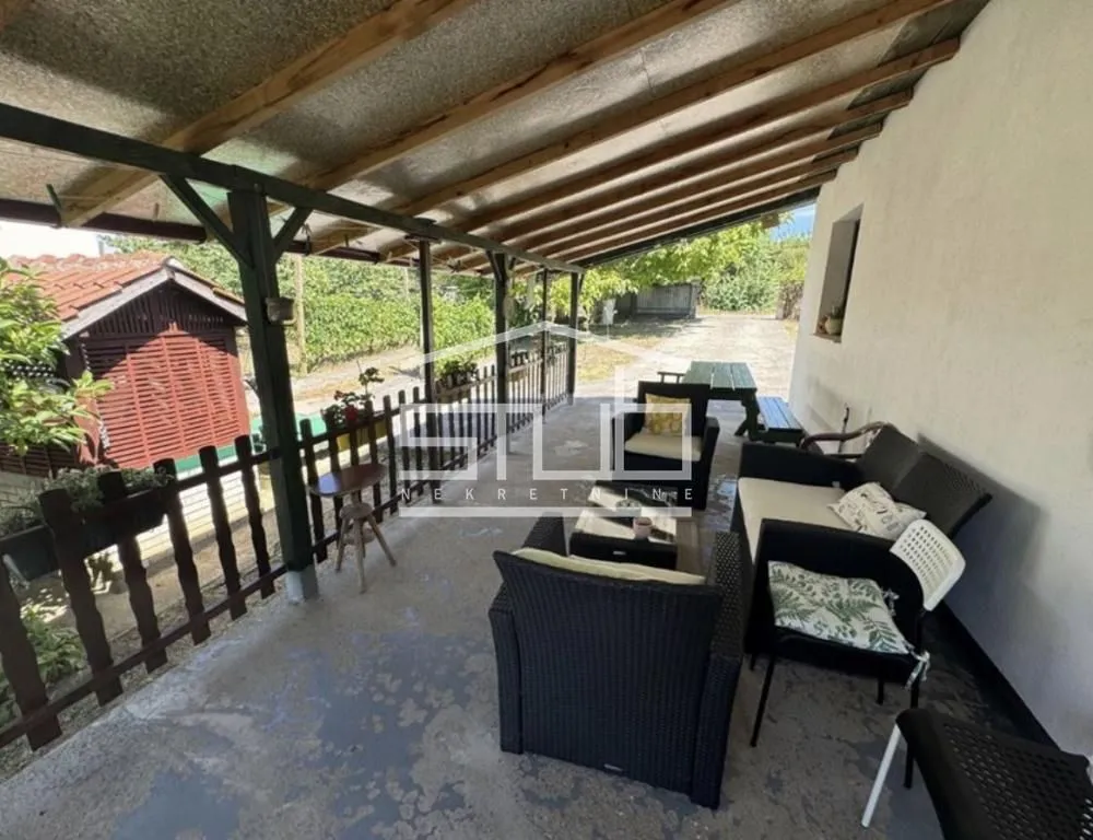 Natkrivena terasa sa garniturom za sedenje u dvorištu.