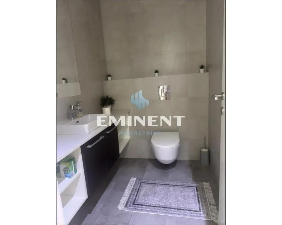 Modern bathroom with a sink, toilet, and grey tiles.