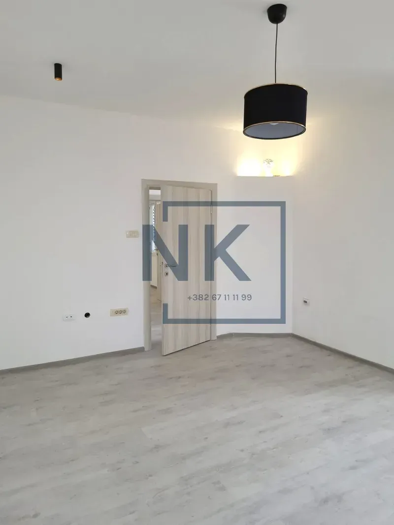 Empty bright room with laminate flooring and an open wooden door.