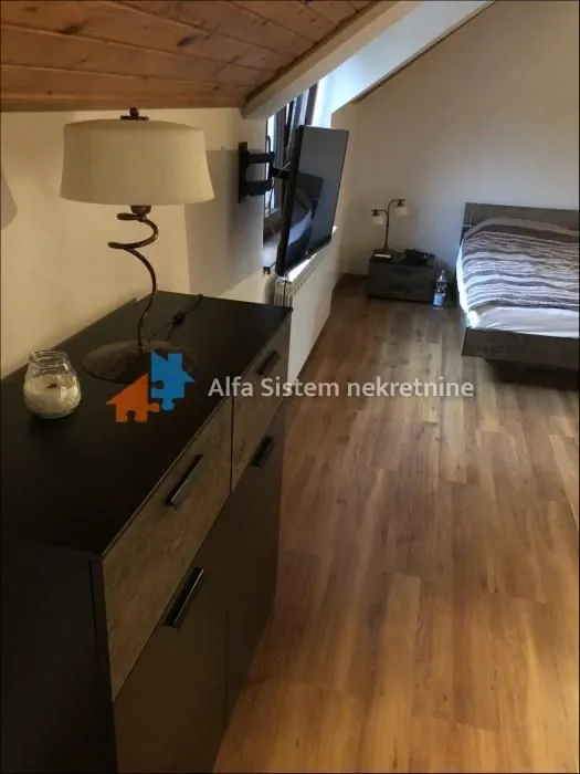 Bedroom with a bed, dresser, and TV in the attic.