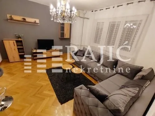 Living room with a sofa, TV, and parquet flooring.