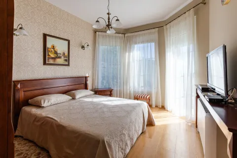 Prostrana spavaća soba sa bračnim krevetom, drvenim namještajem i velikim prozorima sa bijelim zavjesama. - image 42