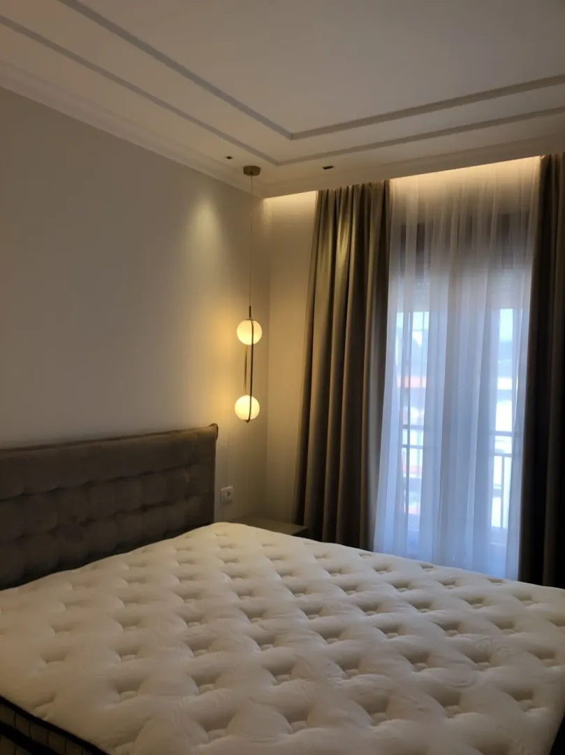 Bright bedroom with modern lighting and a large window.