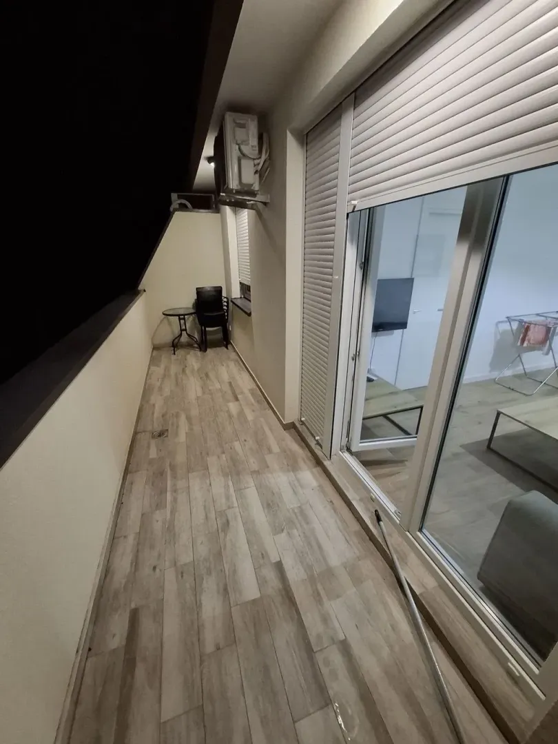 Long covered balcony with wooden flooring and night view.