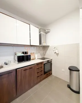 Small kitchen with wooden lower cabinets, white wall cabinets, and built-in appliances. - image 8