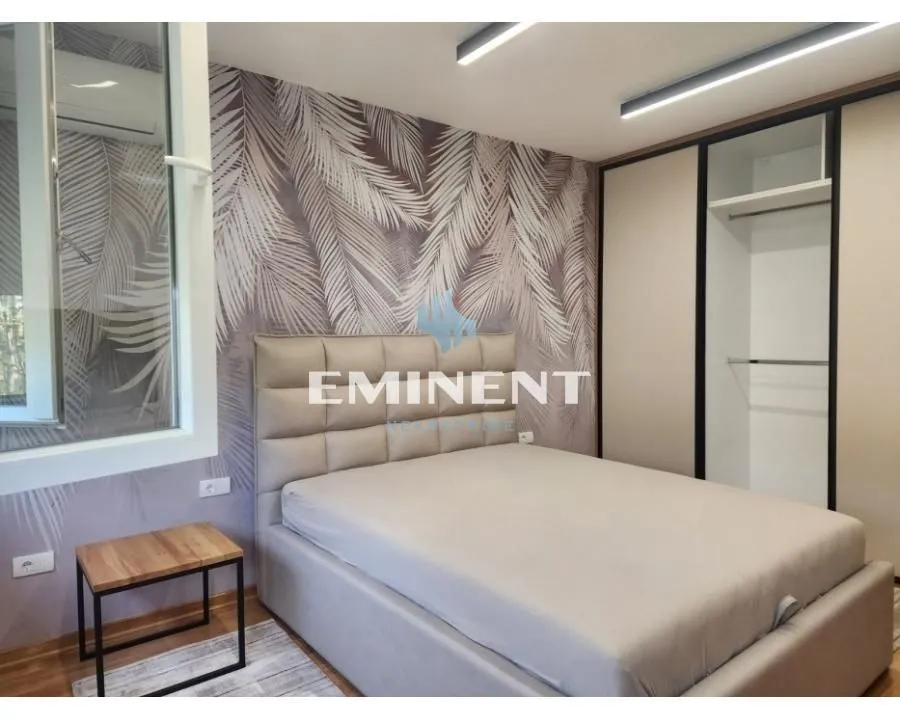 Furnished bedroom with a double bed, wardrobe, and botanical-patterned wallpaper.