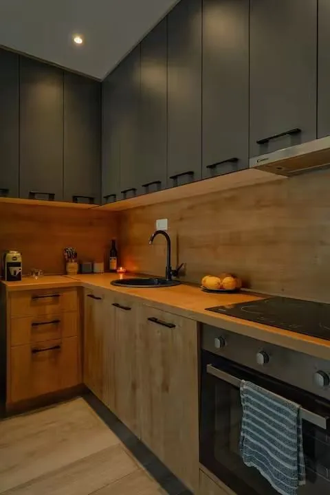 Modern kitchen with dark upper cabinets and wooden countertops.