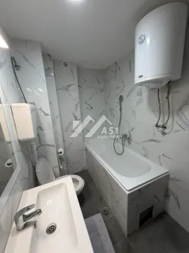 Bathroom equipped with a bathtub, washbasin, toilet, and water heater. - image 4