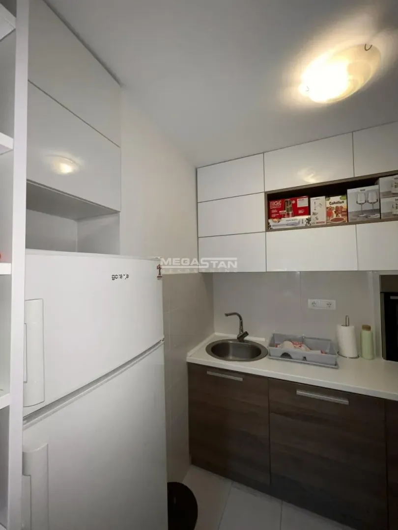 Smaller kitchen with white and wooden cabinets and a refrigerator.
