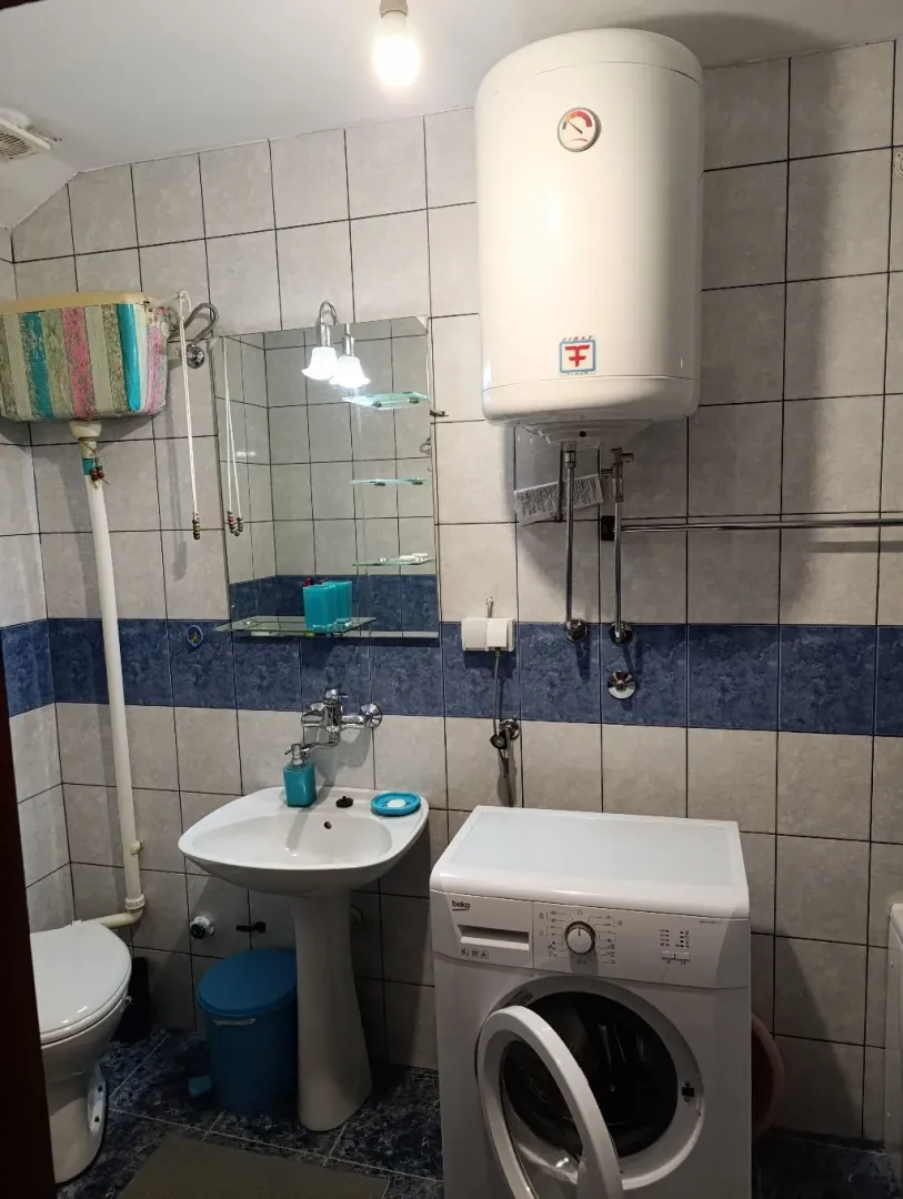 Smaller bathroom with a sink, toilet, water heater and washing machine.