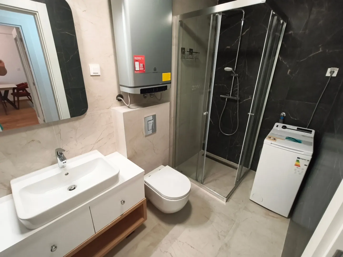 Moderne kupatilo sa tuš kabinom, umivaonikom, WC šoljom i bojlerom.