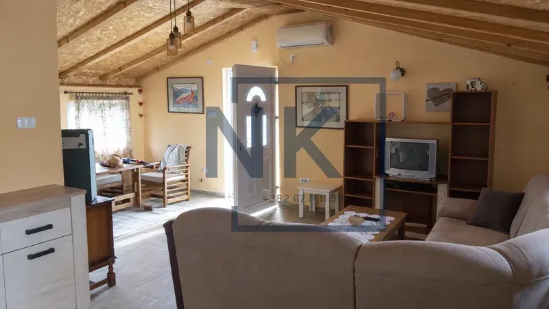 Living room with sofa, TV unit, and wooden ceiling beams.