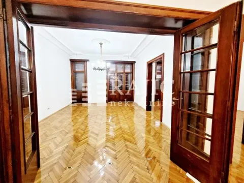 Spacious empty room with parquet flooring and double wooden doors. - image 5