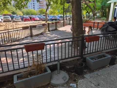 View of the fenced terrace with a wooden floor and a view of the parking lot and surrounding buildings. - image 4