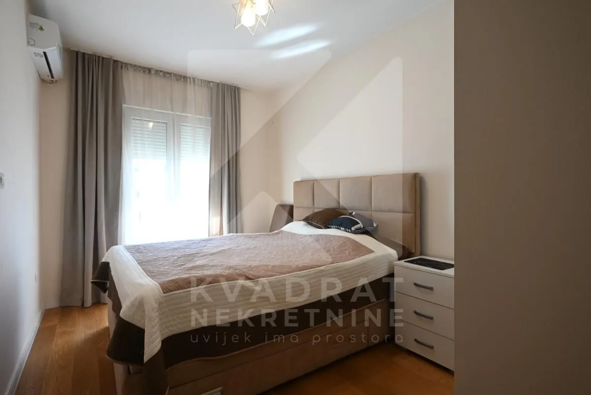 Namještena spavaća soba sa bračnim krevetom i noćnim ormarićem.