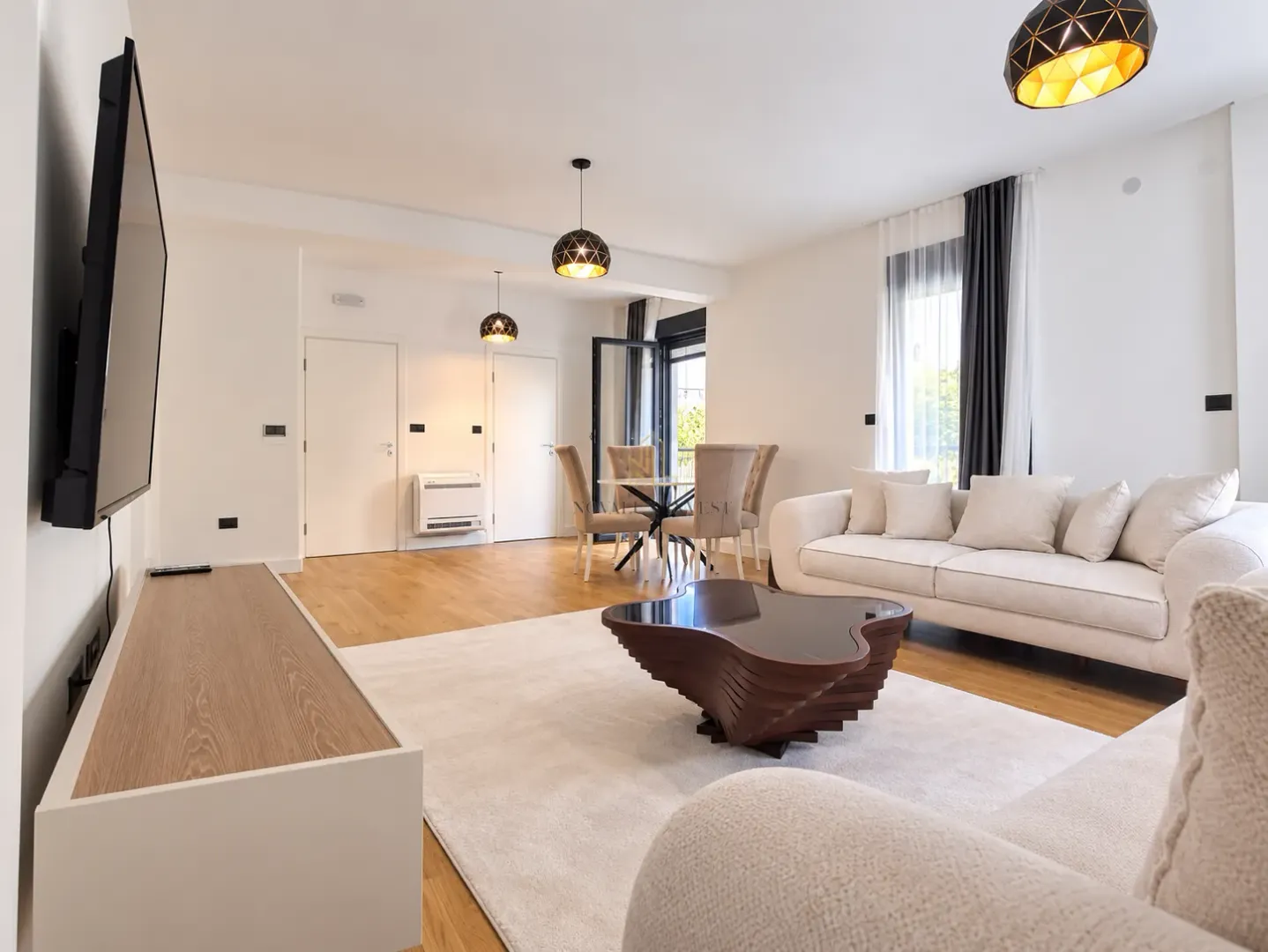 Spacious living room with a sofa, TV, and dining area in the background.