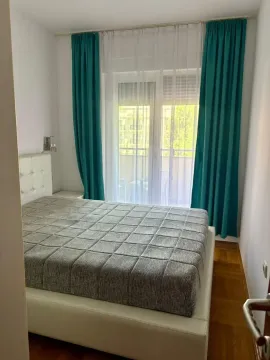 Furnished bedroom with a double bed and balcony doors. - image 4