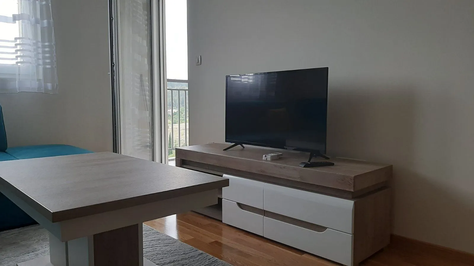Dnevna soba sa televizorom na modernoj komodi i klub stolom.