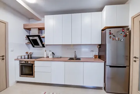 Moderna bijela kuhinja sa drvenom radnom površinom i frižiderom. - image 5