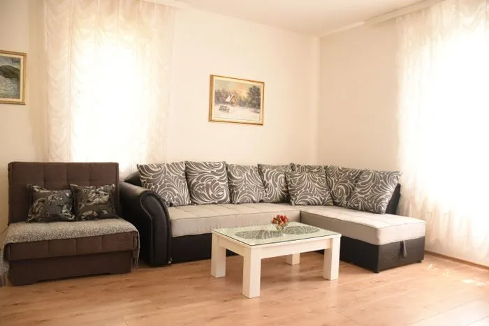 Living room with a sofa set, armchair, coffee table, and windows with curtains.