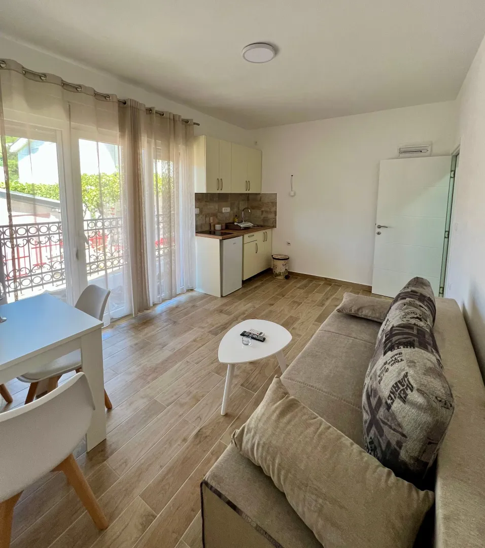 Living room with a sofa, dining area, and a fitted kitchen in the corner.