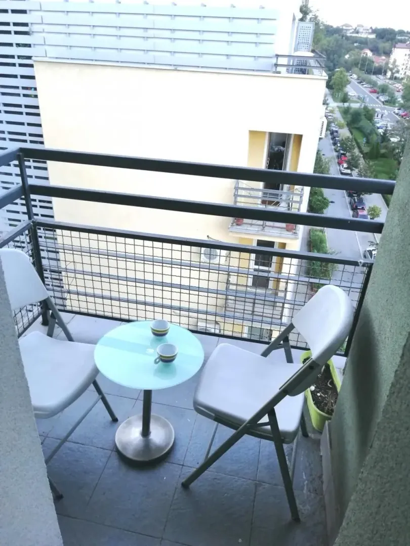 Small balcony furnished with a table and two chairs.