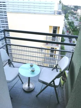 Small balcony furnished with a table and two chairs. - image 4