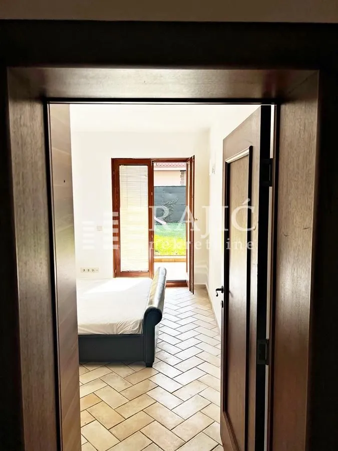 View from the hallway into a bedroom with a bed and courtyard access.